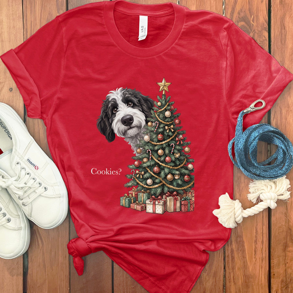 Black and white dog peeking from behind a Christmas tree with presents and text "Cookies?".