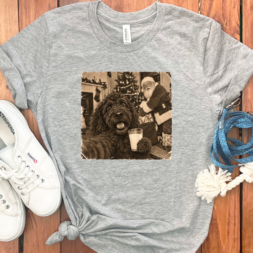 Heather gray crewneck t-shirt featuring a vintage sepia-toned graphic of a dark fluffy dog holding a glass of milk with Santa Claus in the background.