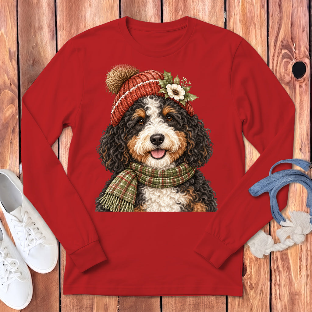 Bernese mountain dog wearing a festive hat and scarf on a red long-sleeve shirt.