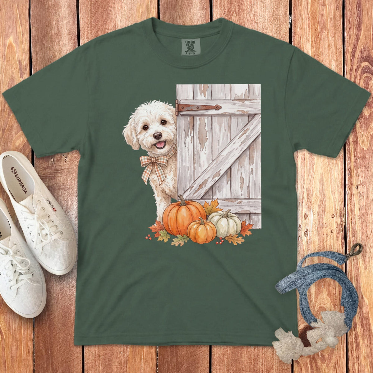 Green t-shirt with a dog peeking behind a rustic door with pumpkins and autumn leaves.