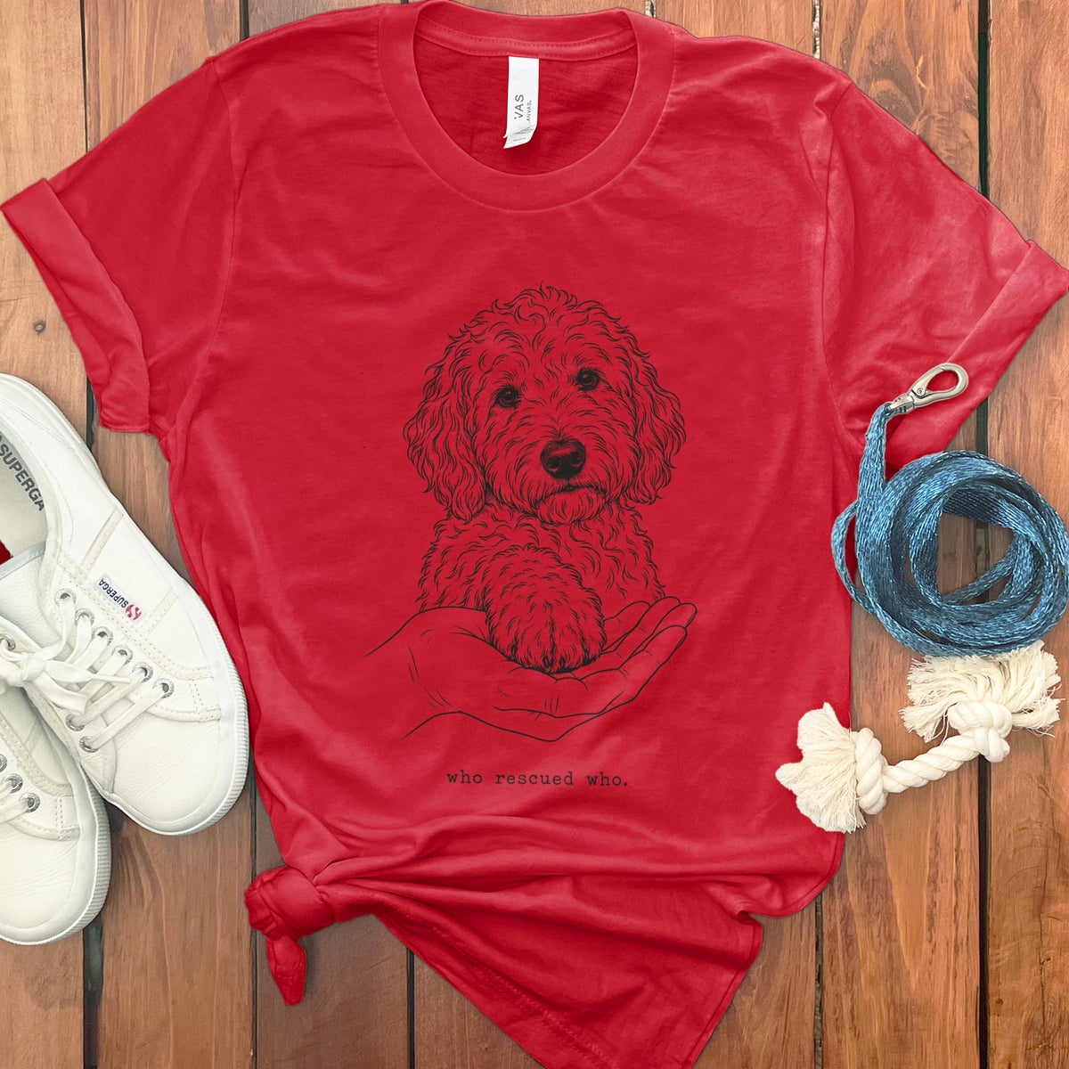Red t-shirt with dog paw in hand graphic and text "who rescued who".