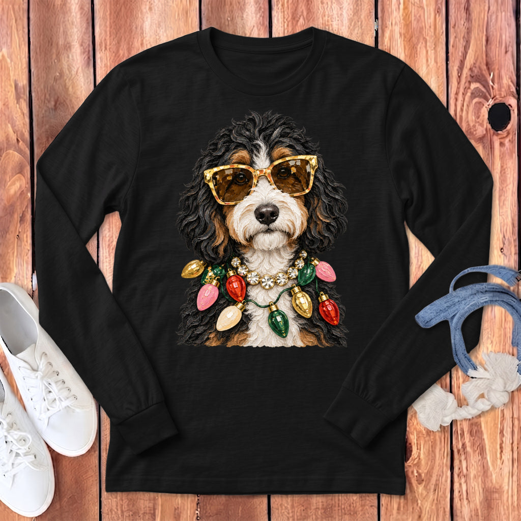 Bernedoodle wearing sunglasses and a string of Christmas lights on a black long-sleeve shirt.