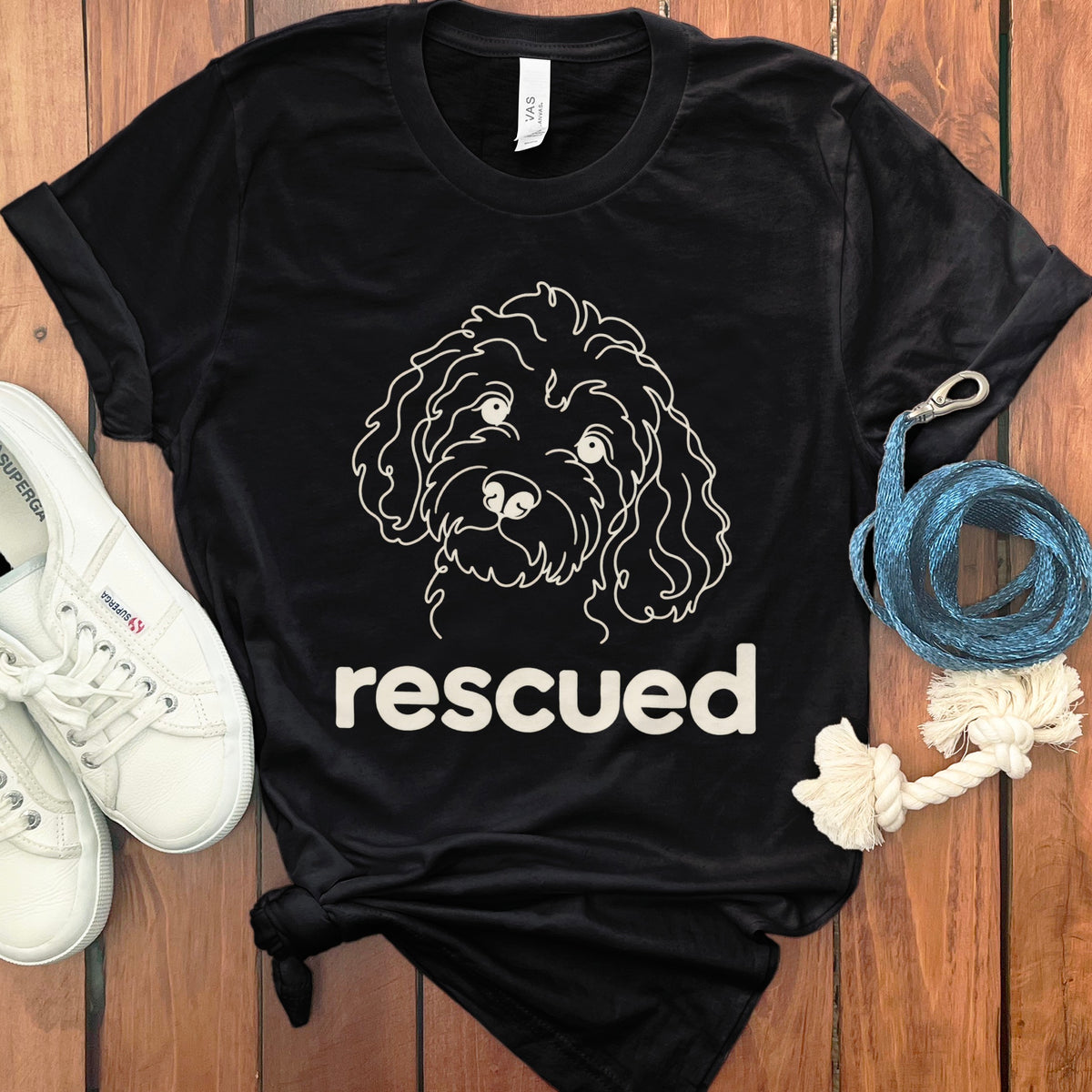 Black t-shirt with a white line drawing of a dog and the word "rescued".