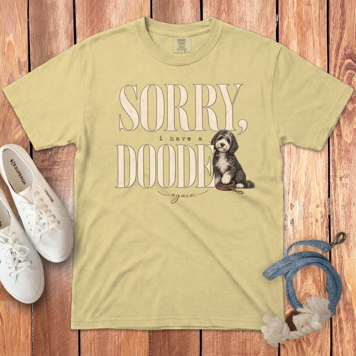 Yellow crewneck t-shirt featuring text that reads SORRY, i have a DOODE again, and an illustration of a doodle dog.