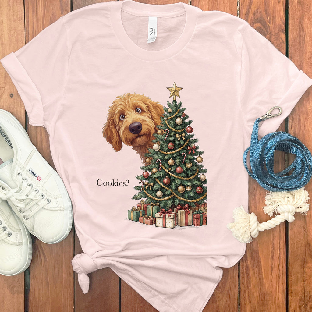 Goldendoodle peeking out from behind a Christmas tree asking "Cookies?".