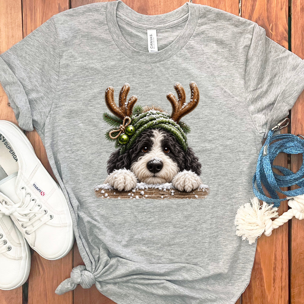 Grey t-shirt with a black and white dog wearing a green winter hat with antlers.
