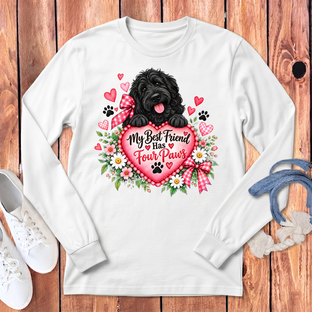 A white long-sleeved shirt features a graphic of a black dog resting paws on a pink heart surrounded by flowers and text reading My Best Friend Has Four Paws.