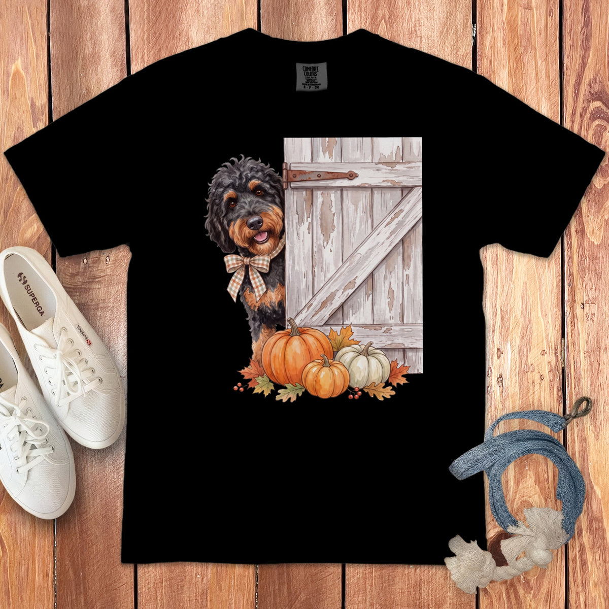 Black t-shirt with a dog peeking from behind a rustic door with pumpkins.