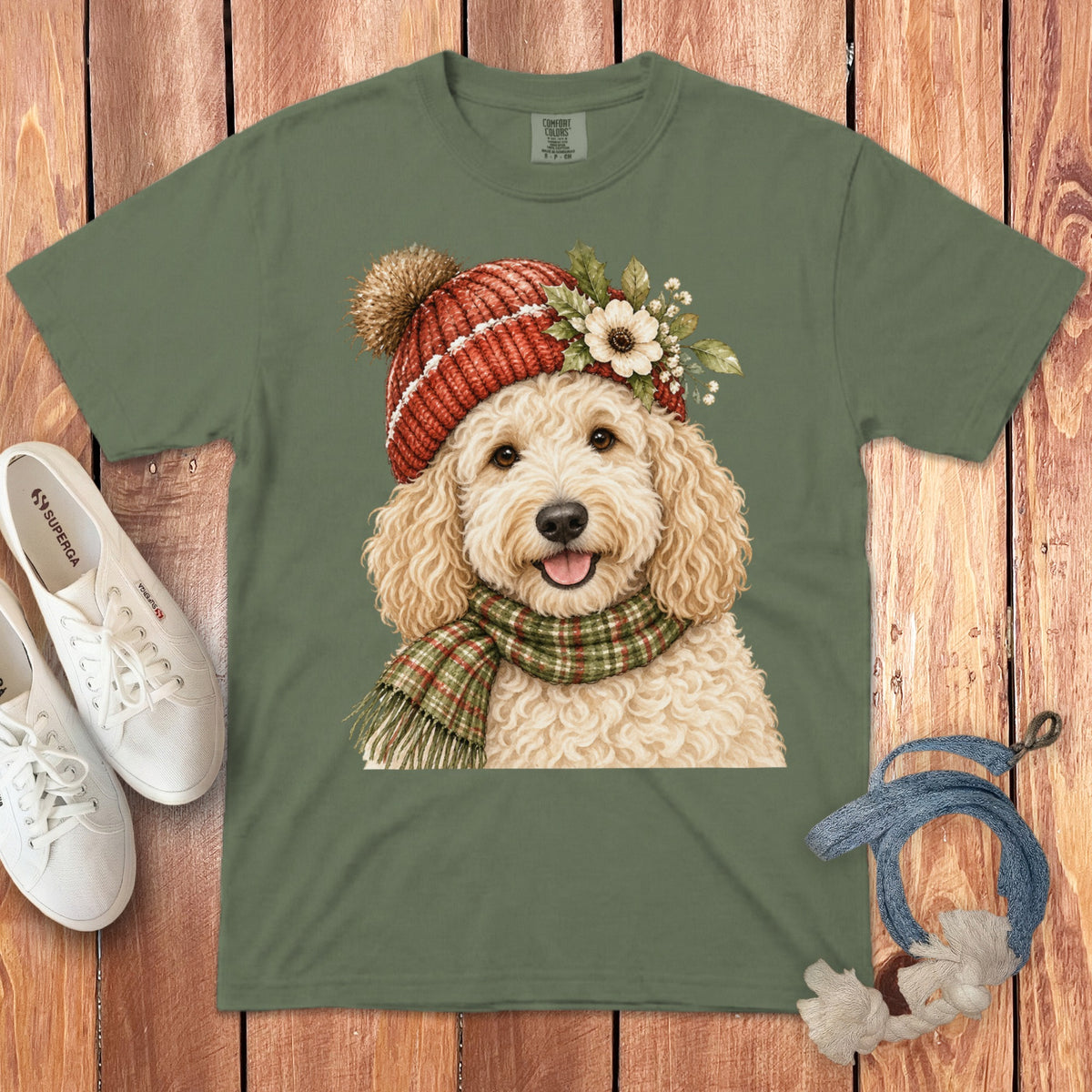 Green t-shirt with a watercolor illustration of a goldendoodle dog wearing a hat and scarf.