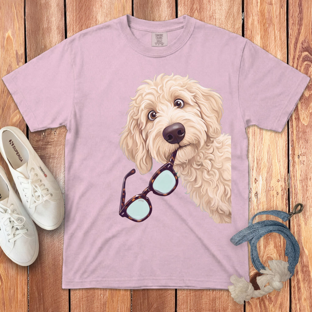 Light pink t-shirt featuring an illustration of a fluffy golden dog holding glasses in its mouth.