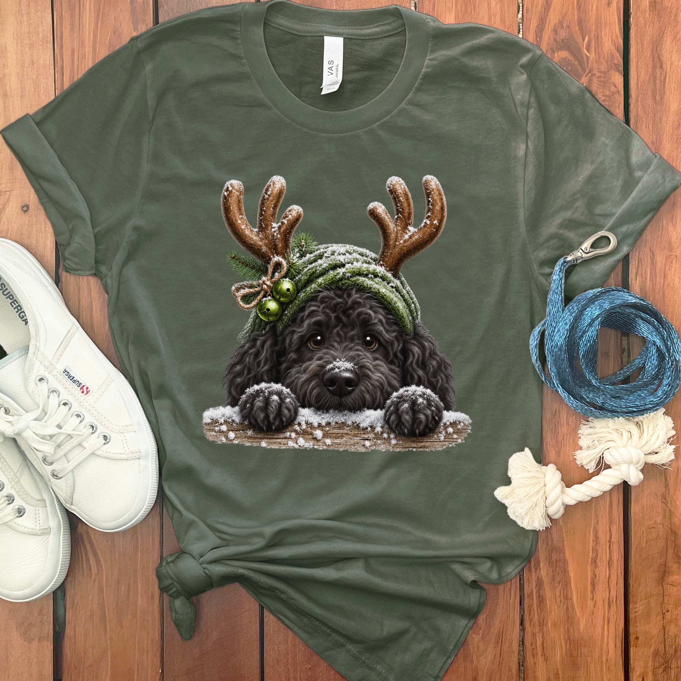 Olive green t-shirt with a black dog wearing reindeer antlers and a winter hat.