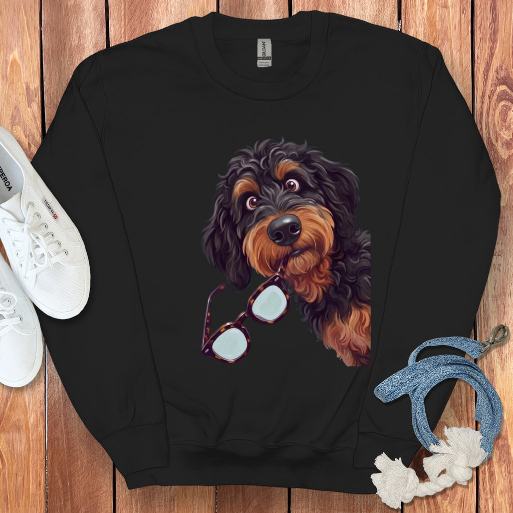 Black crewneck sweatshirt featuring a graphic of a black and tan doodle dog holding glasses in its mouth.