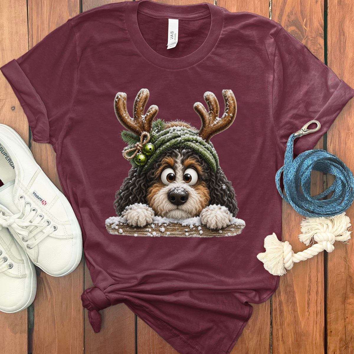 Maroon t-shirt with a fluffy dog wearing a reindeer hat and green scarf.