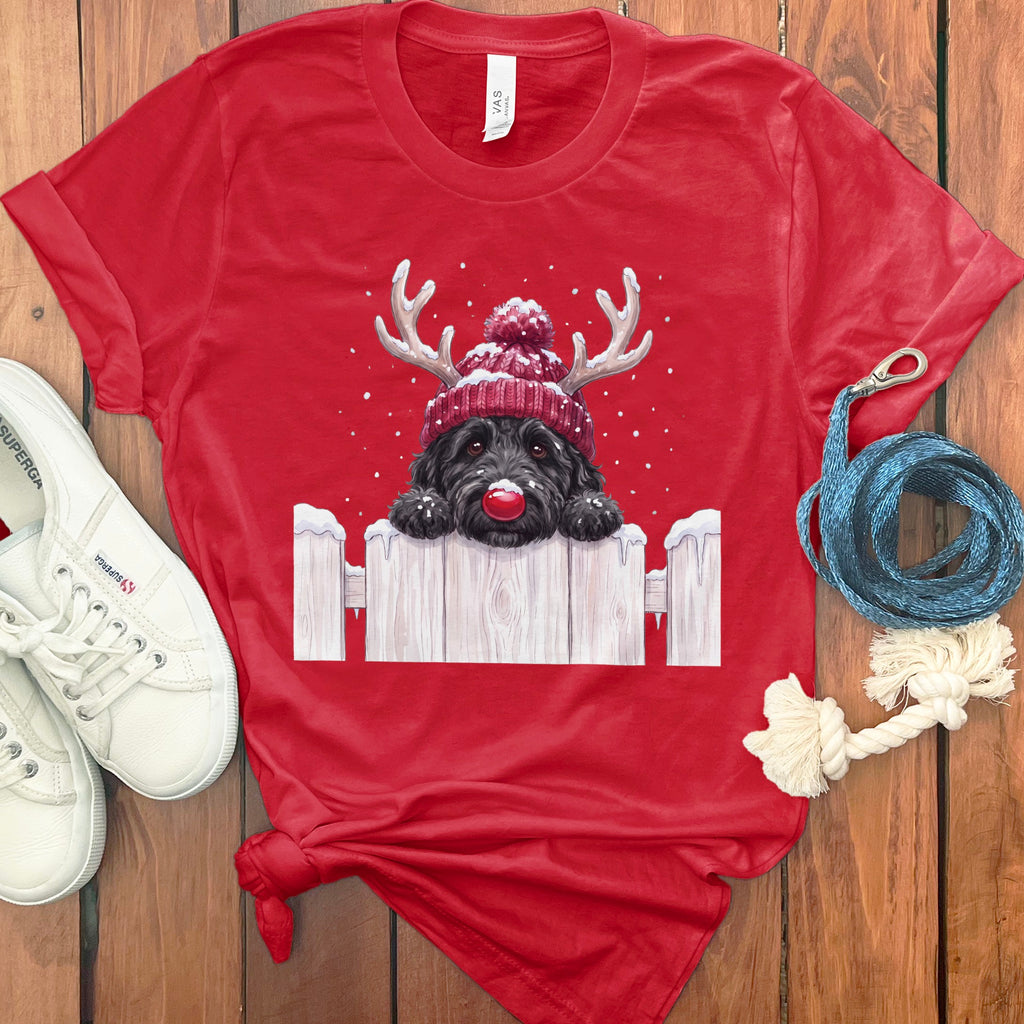 Red t-shirt with a black dog wearing a Santa hat and red nose, peeking over a fence.