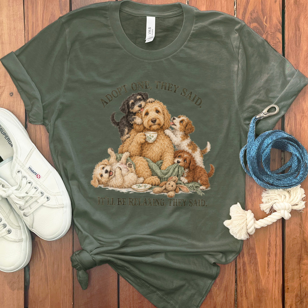 Green t-shirt with a dog illustration and text "ADOPT ONE, THEY SAID. IT'LL BE RELAXING, THEY SAID."
