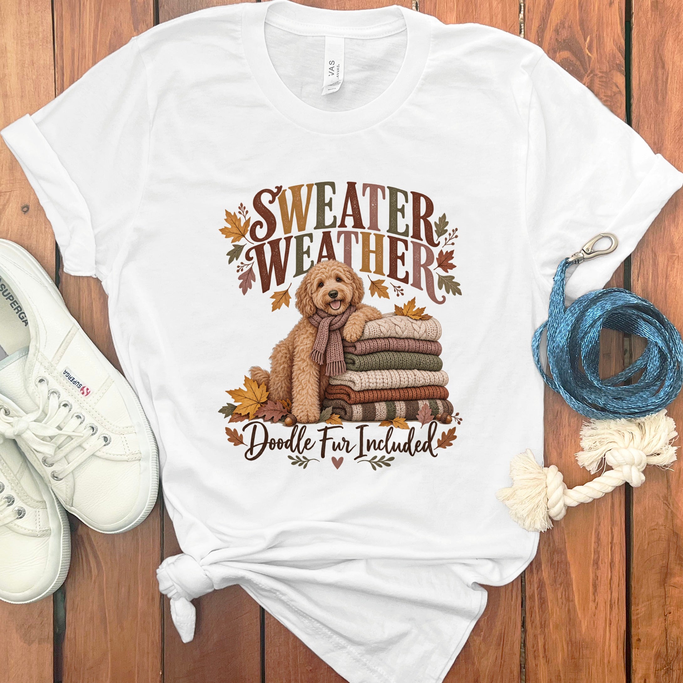 White t-shirt with dog, sweaters, leaves, and "Sweater Weather Doodle Fur Included" text.