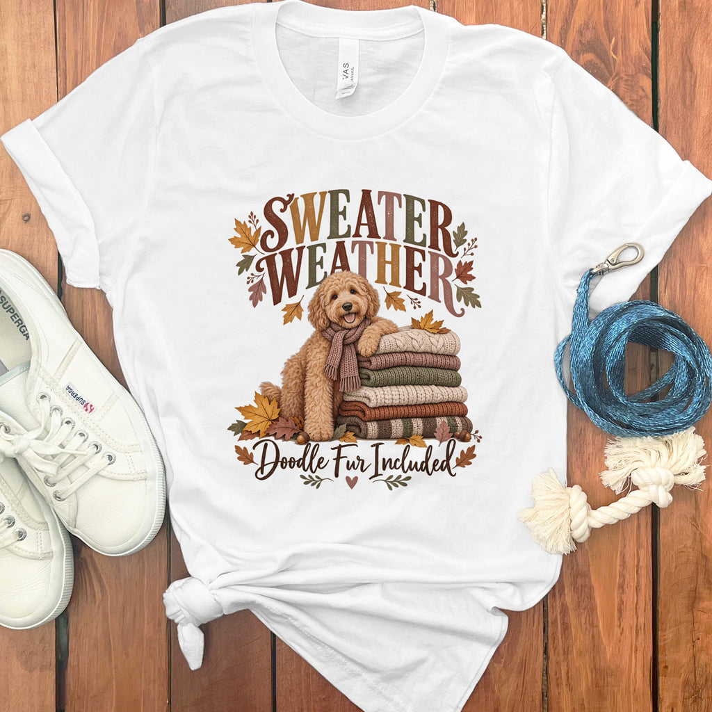 White t-shirt with dog, sweaters, leaves, and "Sweater Weather Doodle Fur Included" text.