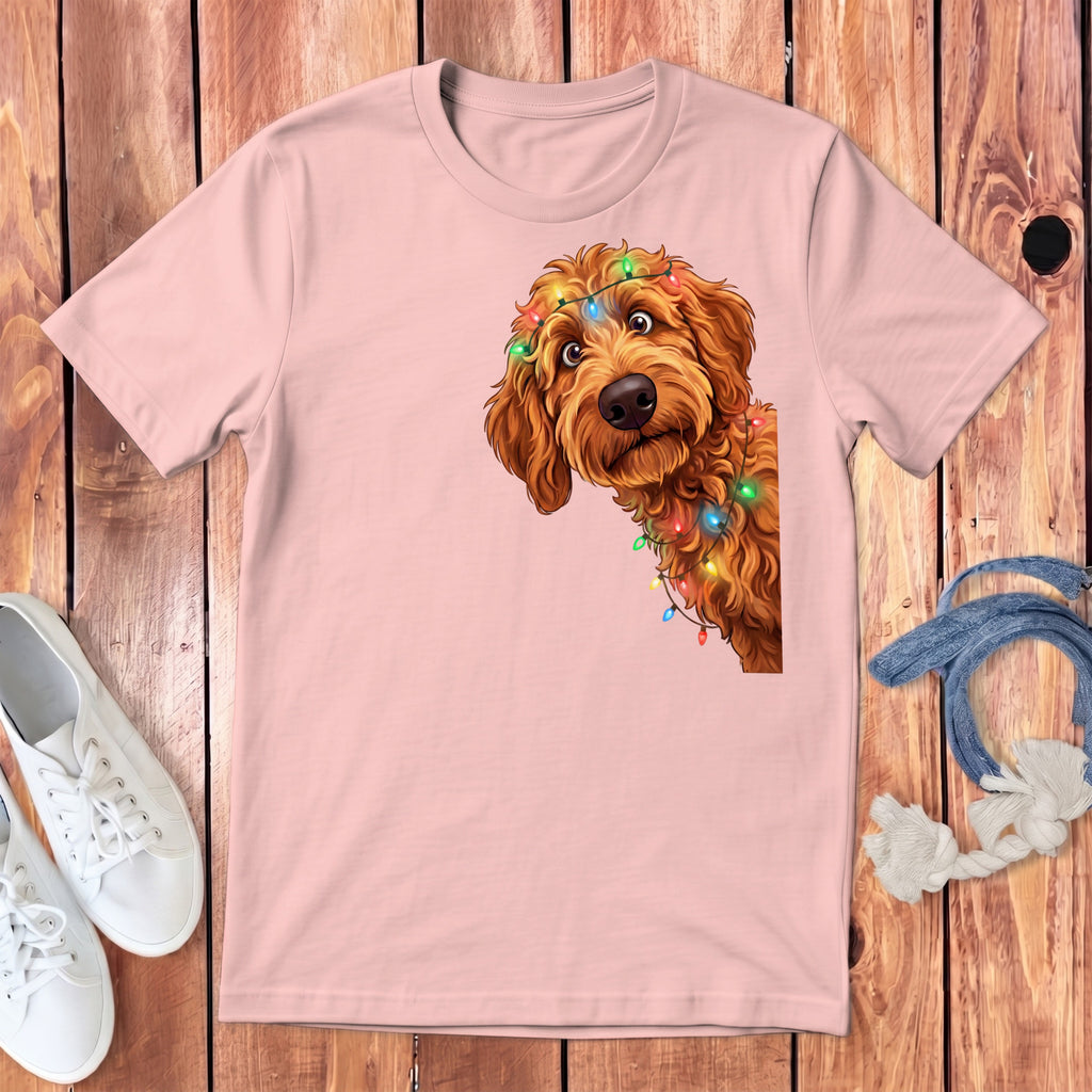 Pink t-shirt with a cartoon goldendoodle wearing colorful Christmas lights.