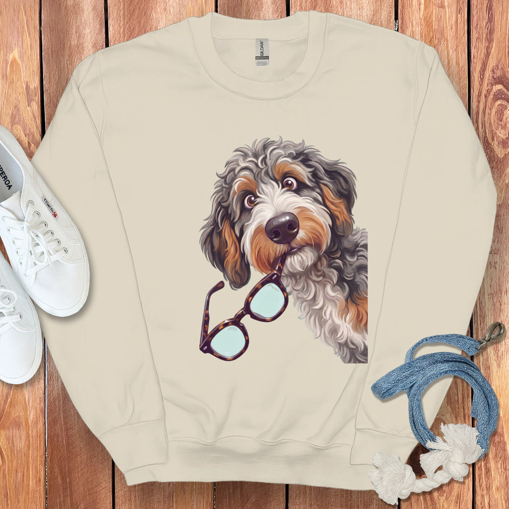 A cream-colored crewneck sweatshirt featuring a graphic of a shaggy dog holding glasses in its mouth.