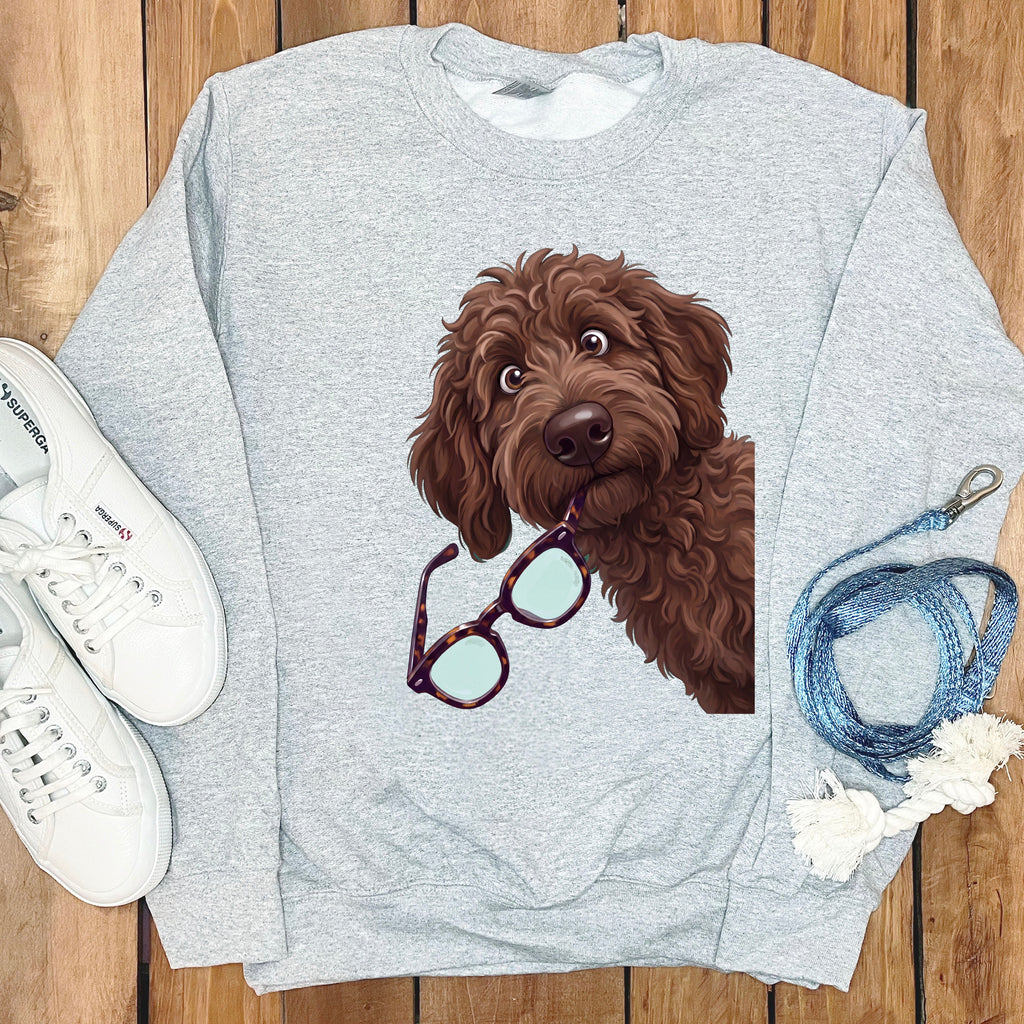 A grey crewneck sweatshirt featuring a cartoon illustration of a brown doodle dog holding glasses in its mouth.