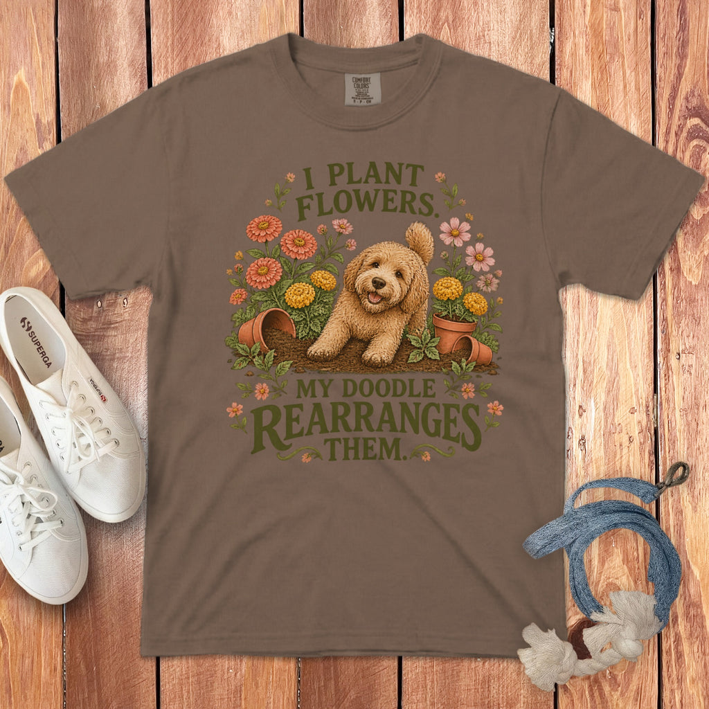 A brown t-shirt featuring a goldendoodle graphic and text that reads I plant flowers. My doodle rearranges them.