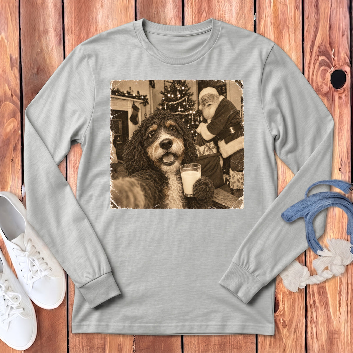A gray long-sleeve t-shirt displays a graphic of a dog holding a glass of milk with Santa Claus in the background.