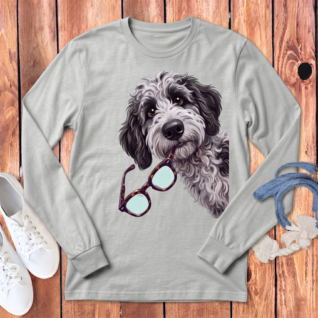 A grey long-sleeved crewneck t-shirt featuring a graphic of a shaggy black and white doodle dog holding glasses in its mouth.