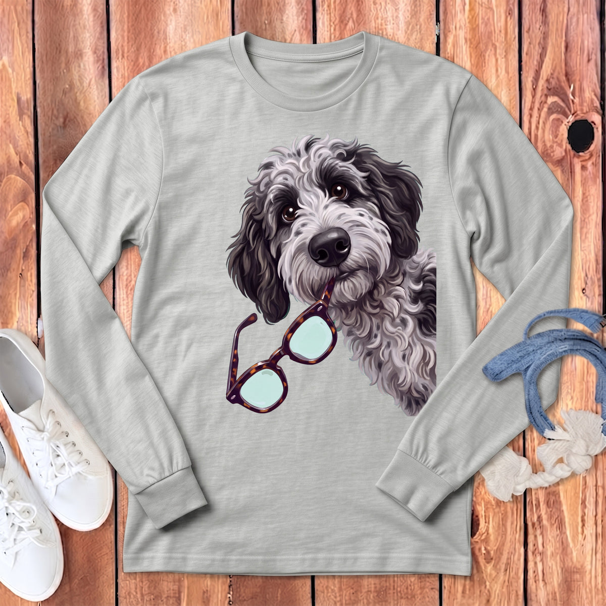 A grey long-sleeved crewneck t-shirt featuring a graphic of a shaggy black and white doodle dog holding glasses in its mouth.