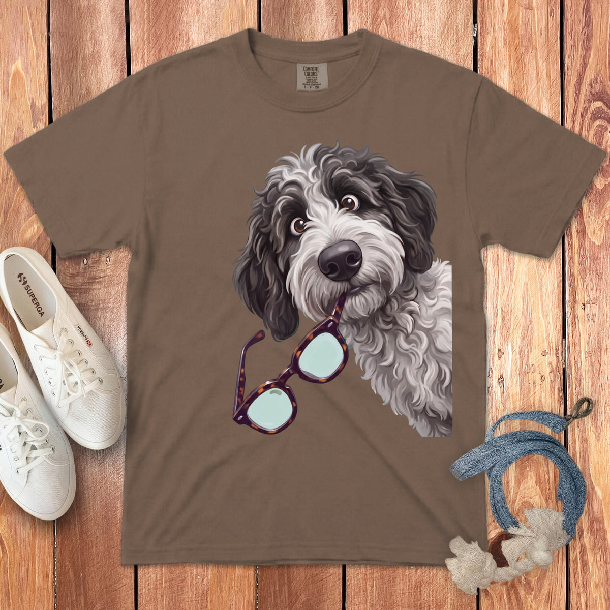 Brown t-shirt featuring an illustration of a fluffy black and white dog holding glasses in its mouth.