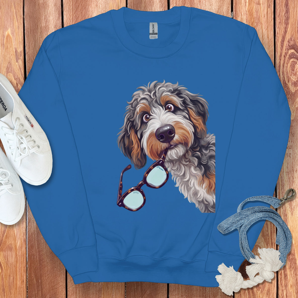 Bright blue crewneck sweatshirt featuring a graphic of a fluffy dog holding glasses in its mouth.