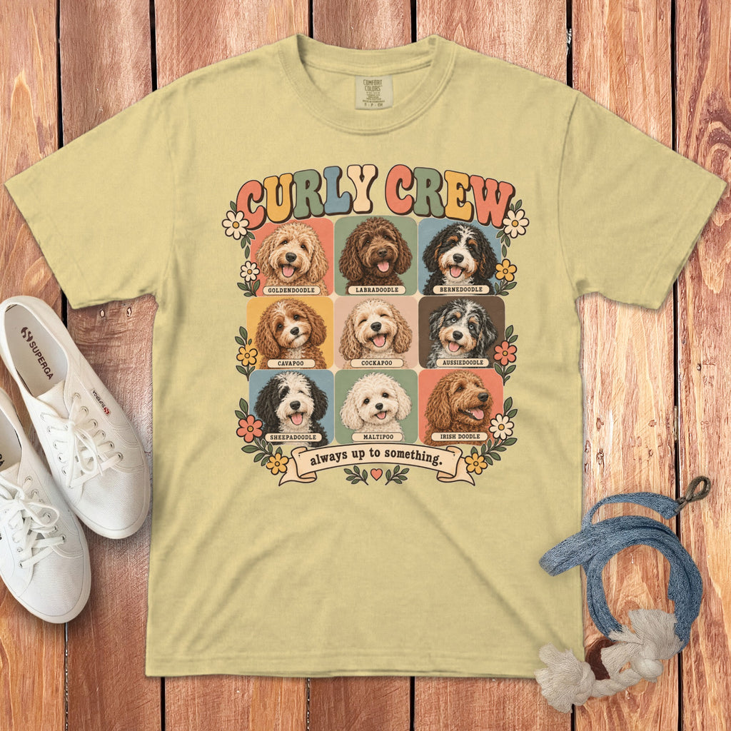 A yellow t-shirt featuring a grid of nine doodle dog illustrations with the text Curly Crew always up to something.
