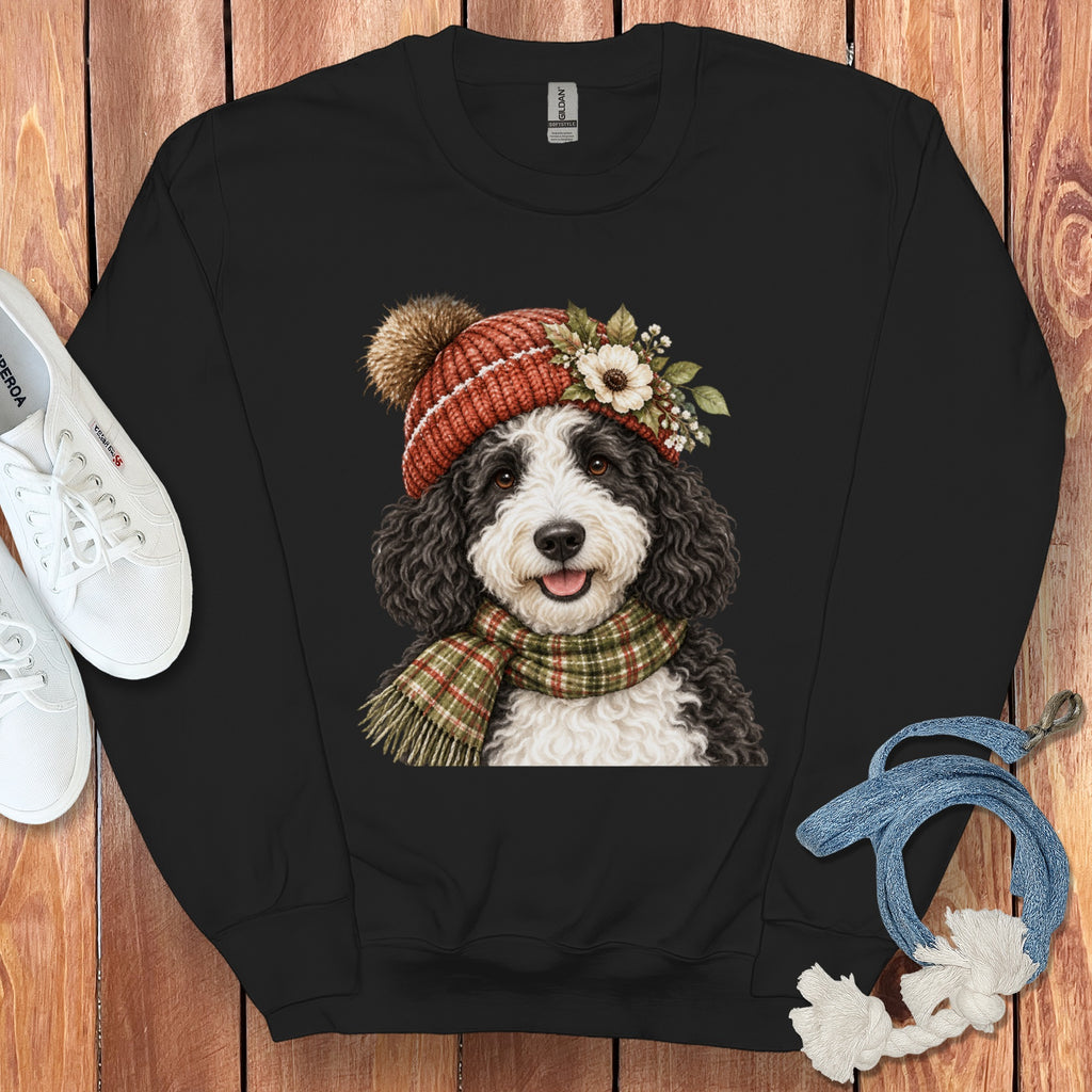 Black sweatshirt with a Bernedoodle wearing a knitted hat and scarf.
