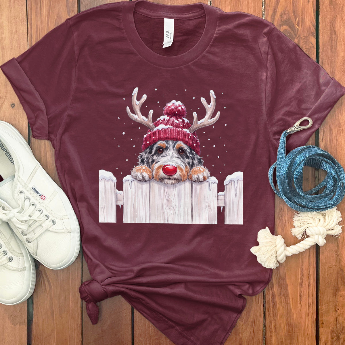 Maroon t-shirt with a Christmas dog graphic peeking over a fence.