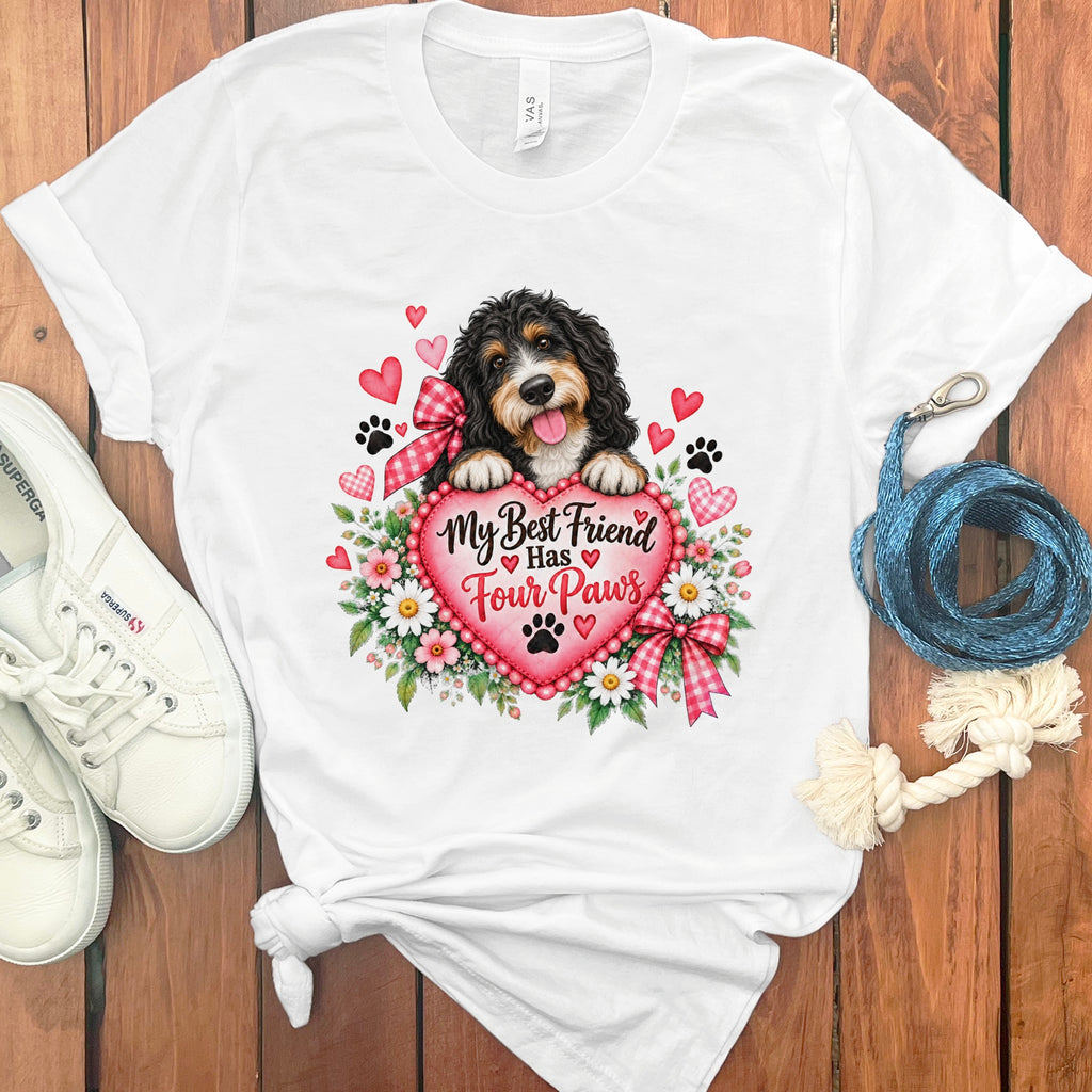 White t-shirt with a graphic of a Bernedoodle dog holding a pink heart that says My Best Friend Has Four Paws.