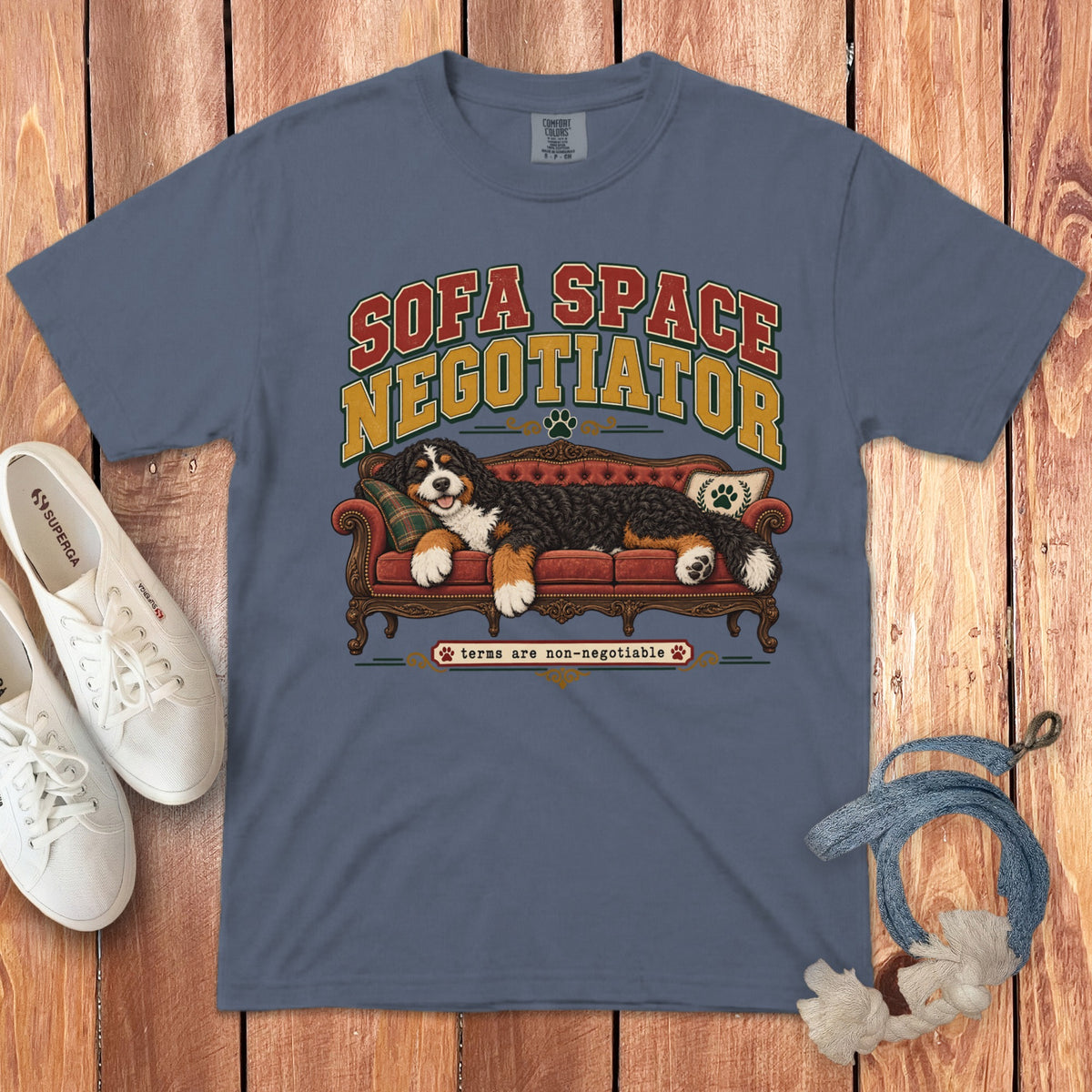 Slate blue t-shirt featuring graphic text and a Bernese Mountain Dog resting on a red sofa.