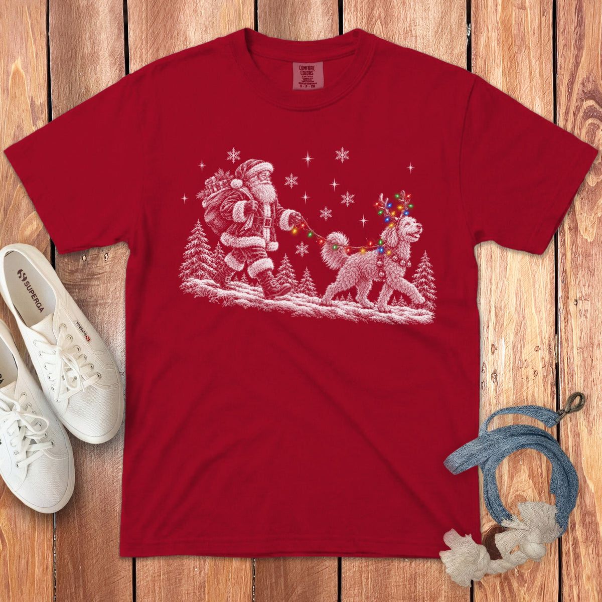 Red t-shirt featuring a white graphic of Santa walking a fluffy dog wearing reindeer antlers and Christmas lights.