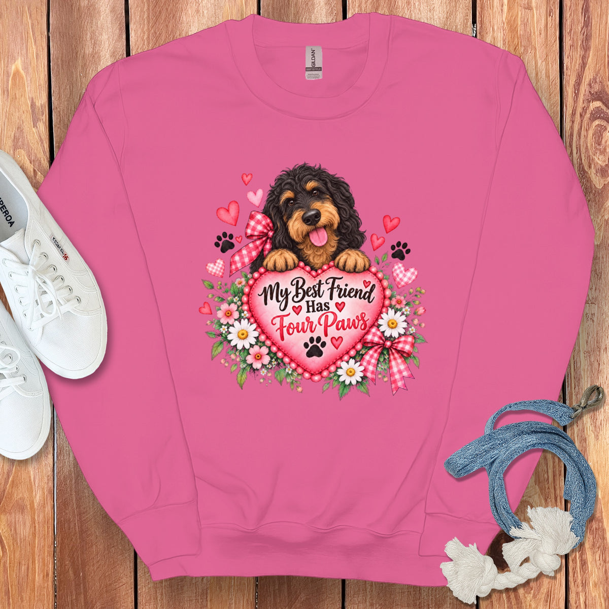 A pink crewneck sweatshirt featuring a graphic of a dog, hearts, flowers, and the text My Best Friend Has Four Paws.