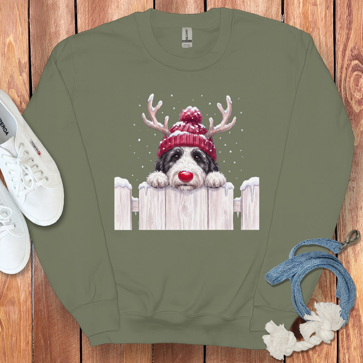 Crewneck sweatshirt with a black and white dog wearing a red knit hat and antlers.