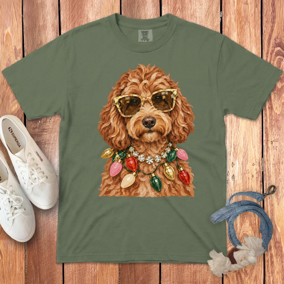 Olive green t-shirt with a doodle wearing sunglasses and Christmas lights.