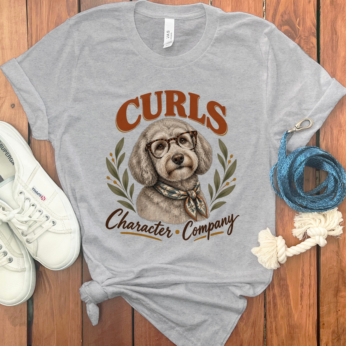 Grey t-shirt with a poodle wearing glasses and scarf, text says "Curls Character Company".