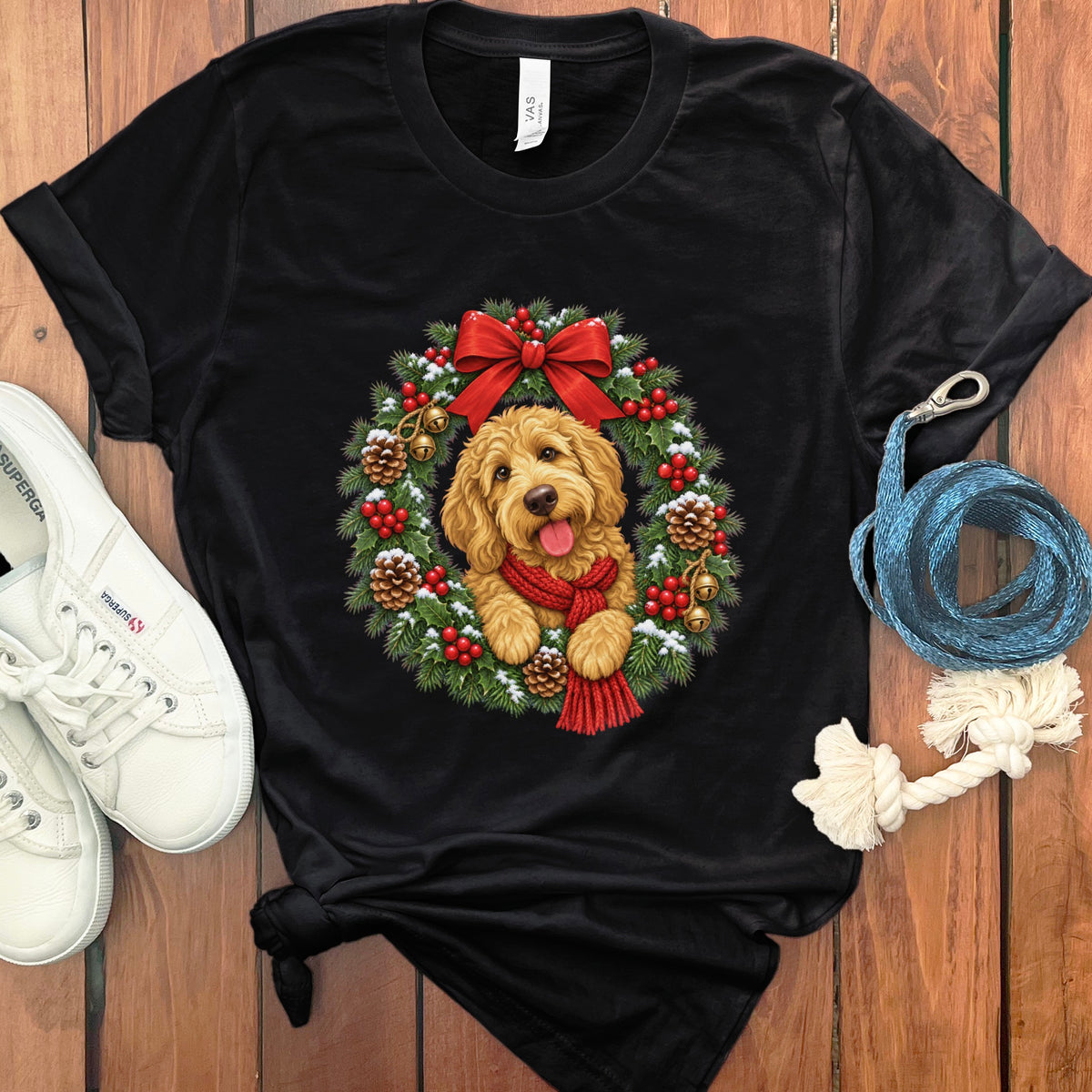 A black t-shirt featuring a goldendoodle wearing a red scarf inside a Christmas wreath.
