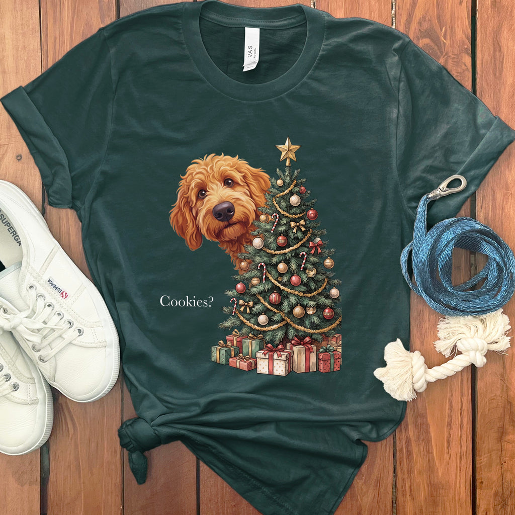 Green t-shirt with a goldendoodle peeking behind a decorated Christmas tree and presents.
