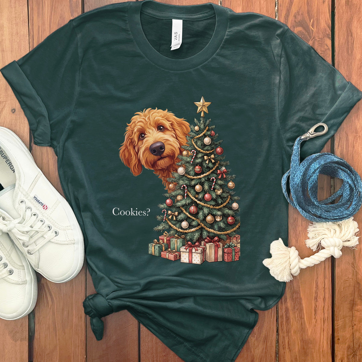 Green t-shirt with a goldendoodle peeking behind a decorated Christmas tree and presents.