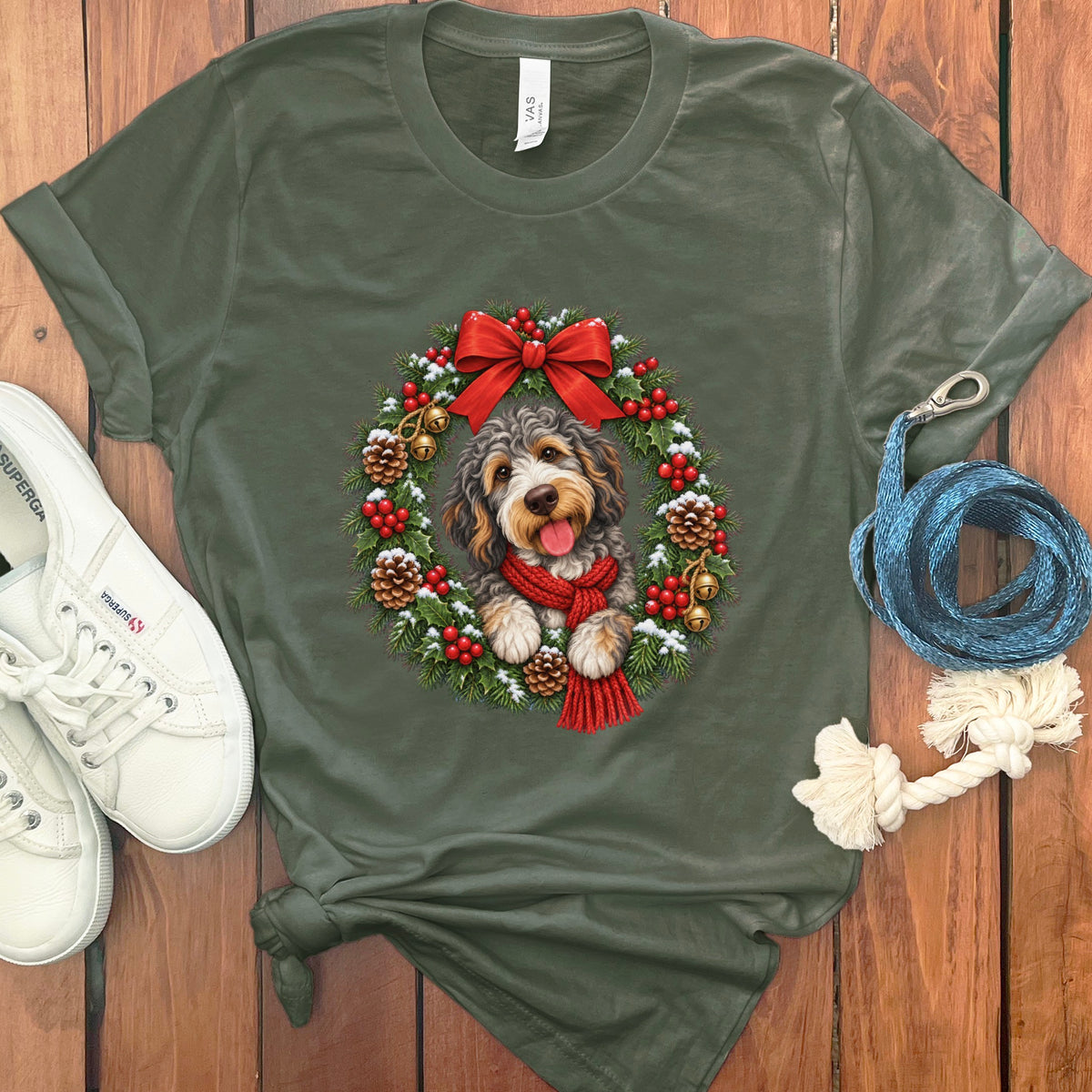 Olive green t-shirt featuring a doodle dog wearing a red scarf inside a Christmas wreath.