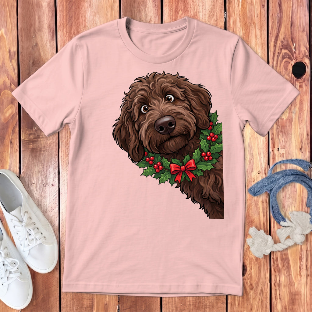 Pink t-shirt with a cartoon brown doodle dog wearing a holly wreath with red bow.