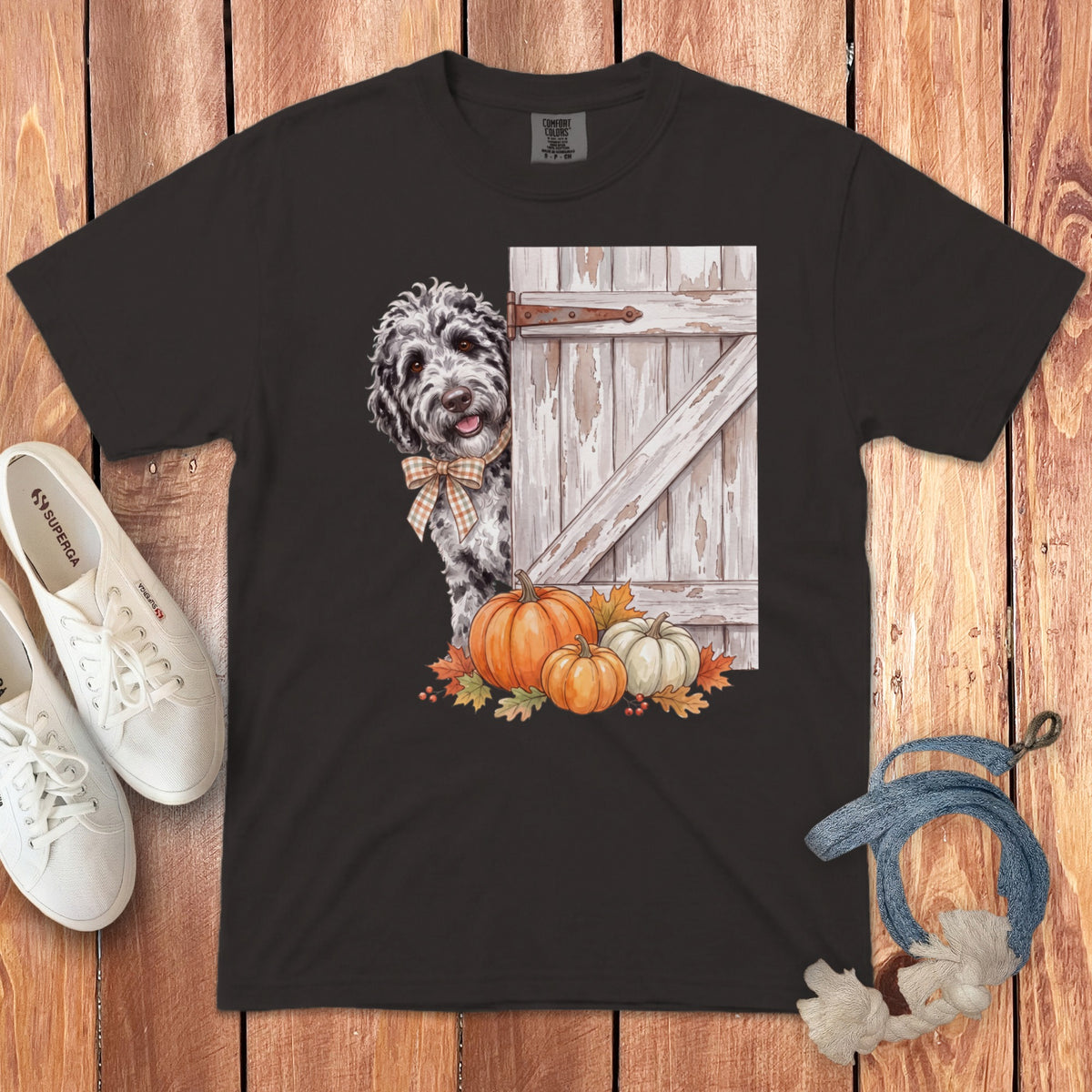 Black t-shirt with dog peeking from behind a rustic barn door with pumpkins.