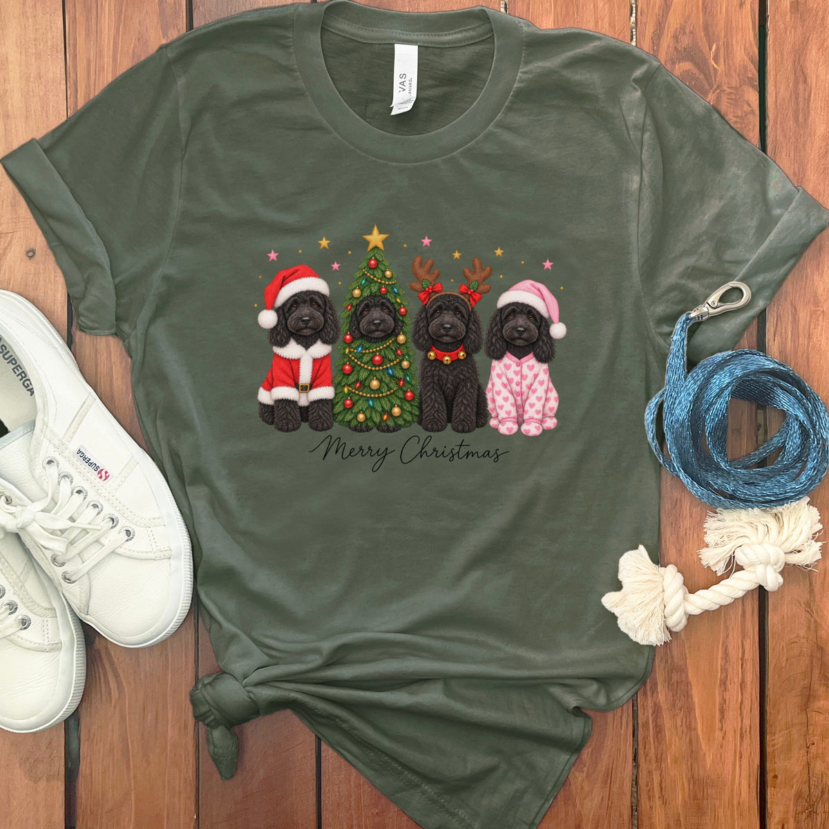 Olive green t-shirt featuring a Christmas graphic of four black doodles, a decorated tree, and Merry Christmas text.