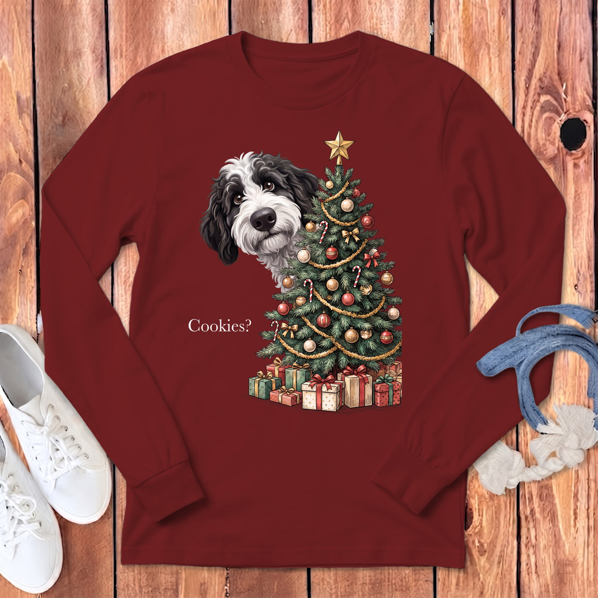 Black and white dog peeks from behind a decorated Christmas tree with presents, asking "Cookies?".