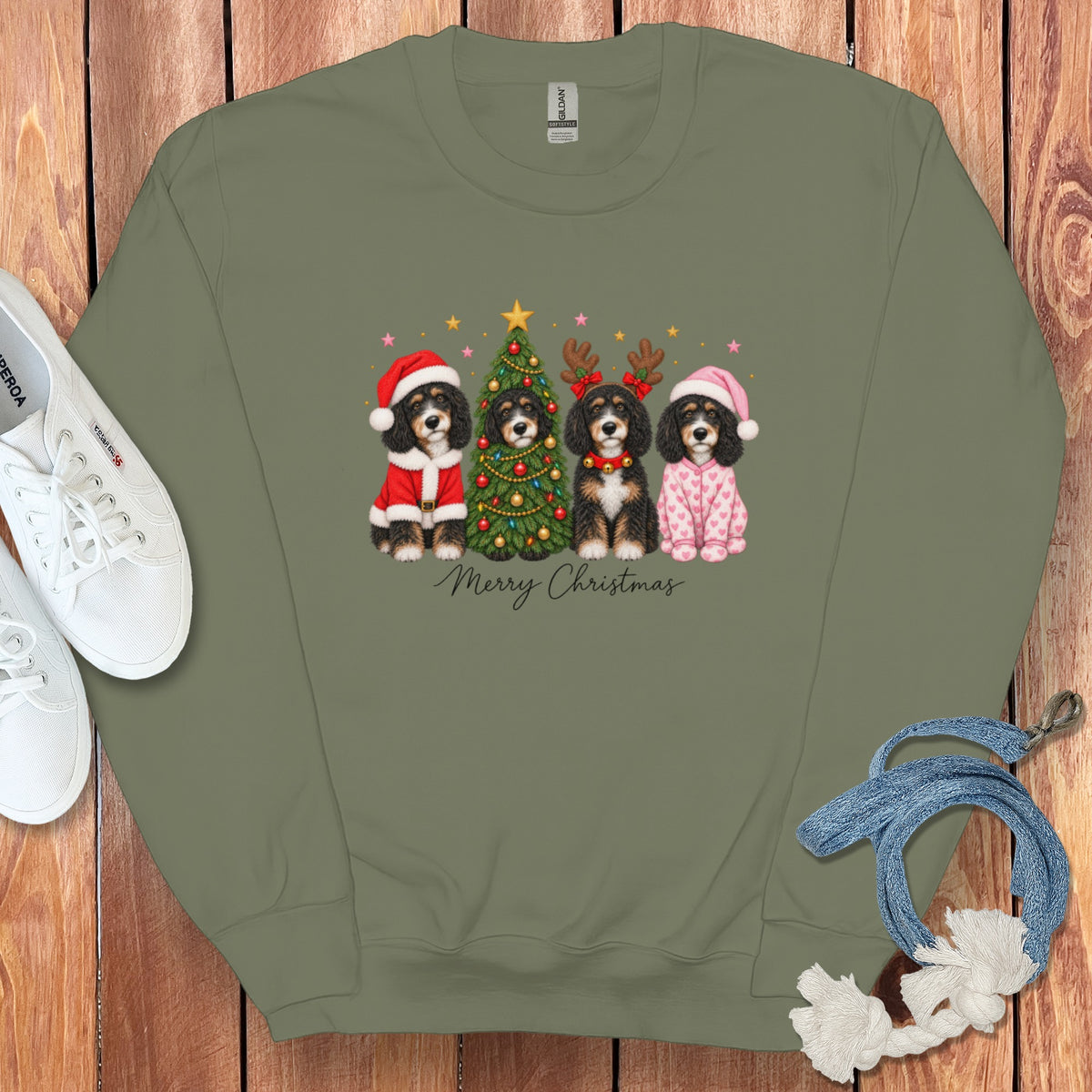 Olive green crewneck sweatshirt featuring a graphic of four Bernedoodles in Christmas attire surrounding a decorated tree.