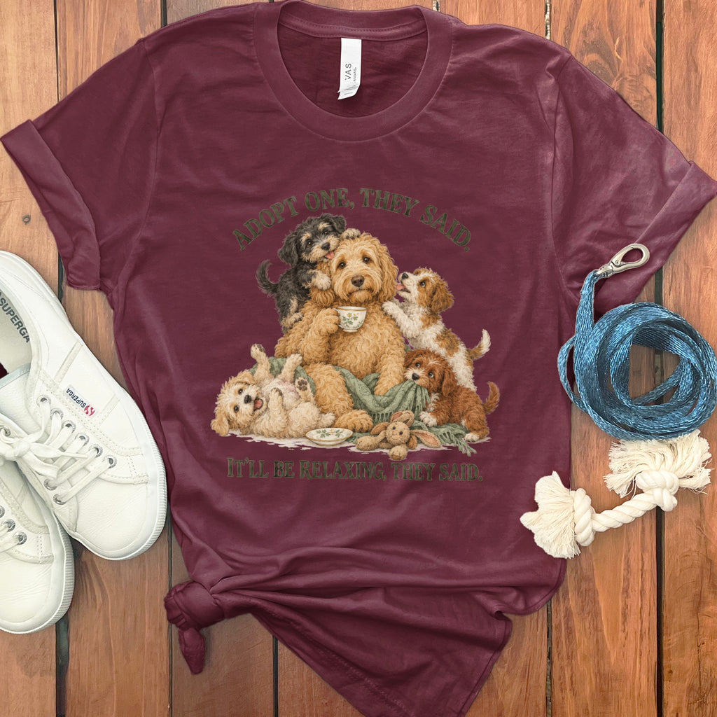 Maroon t-shirt with illustration of a family of dogs and text "Adopt One, They Said."